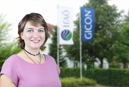 Sandra Esch steht vor Betriebsgebäude mit zwei Flaggen.